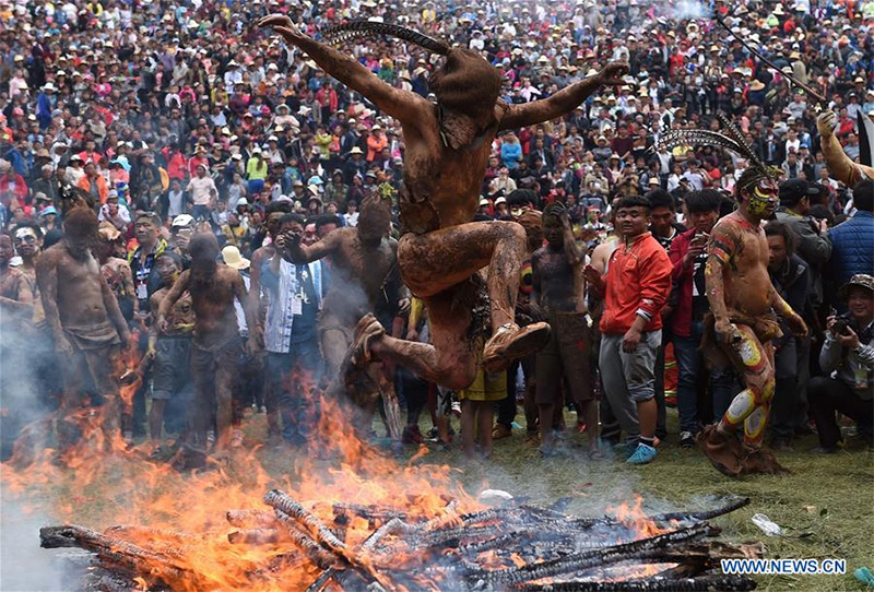 A man of Yi ethnic group jumps over a bonfire to drive out ill fortune during the annual fire worshipping festival, which falls on the third day of the second month in the Chinese lunar calendar at Xiyi Township under Mile City, southwest China